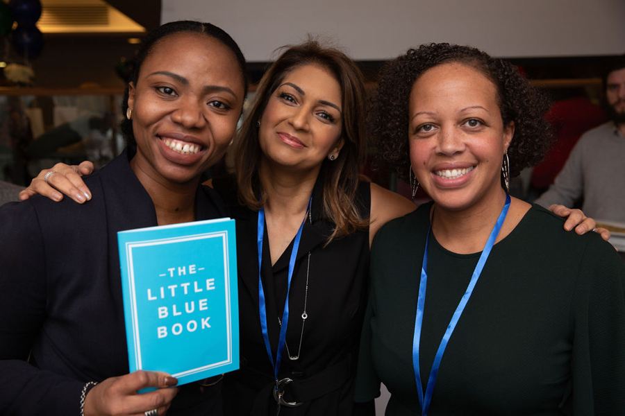 Aduke with two guests holding The Little Blue Book